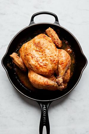 a whole roasted chicken seasoned with salt in a cast iron skillet