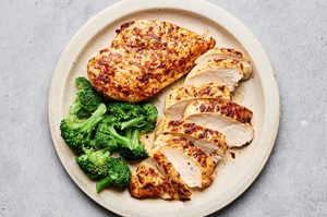 Air fryer chicken breasts cooked until golden sliced on a plate served with steamed broccoli