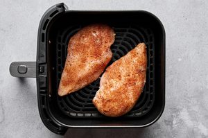 chicken breast rubbed with olive oil, salt, paprika, garlic powder, onion powder and black pepper cooking in an air fryer