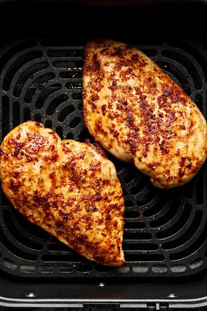 juicy, golden Air fryer chicken breasts perfectly seasoned inside an air fryer, a healthy quick protein option