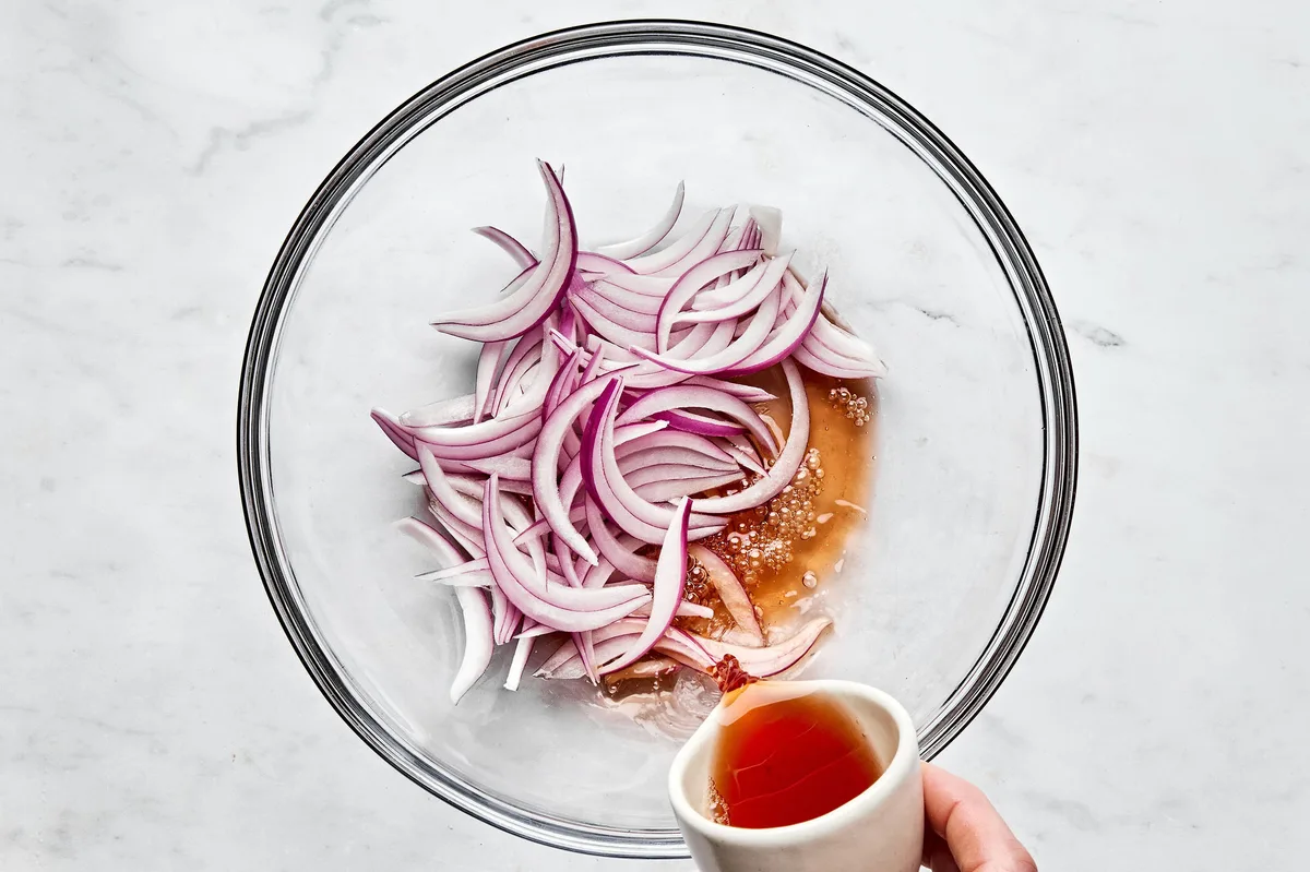 thinly sliced red onion being soaked in red wine vinegar
