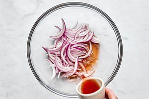 thinly sliced red onion being soaked in red wine vinegar