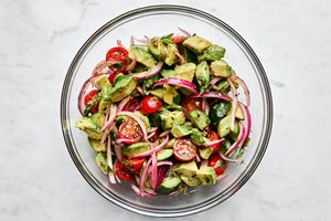 a bowl of avocado salad made with tomatoes, cucumbers, serrano pepper, cilantro, mint and homemade vinaigrette