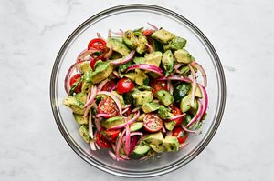a bowl of avocado salad made with tomatoes, cucumbers, serrano pepper, cilantro, mint and homemade vinaigrette
