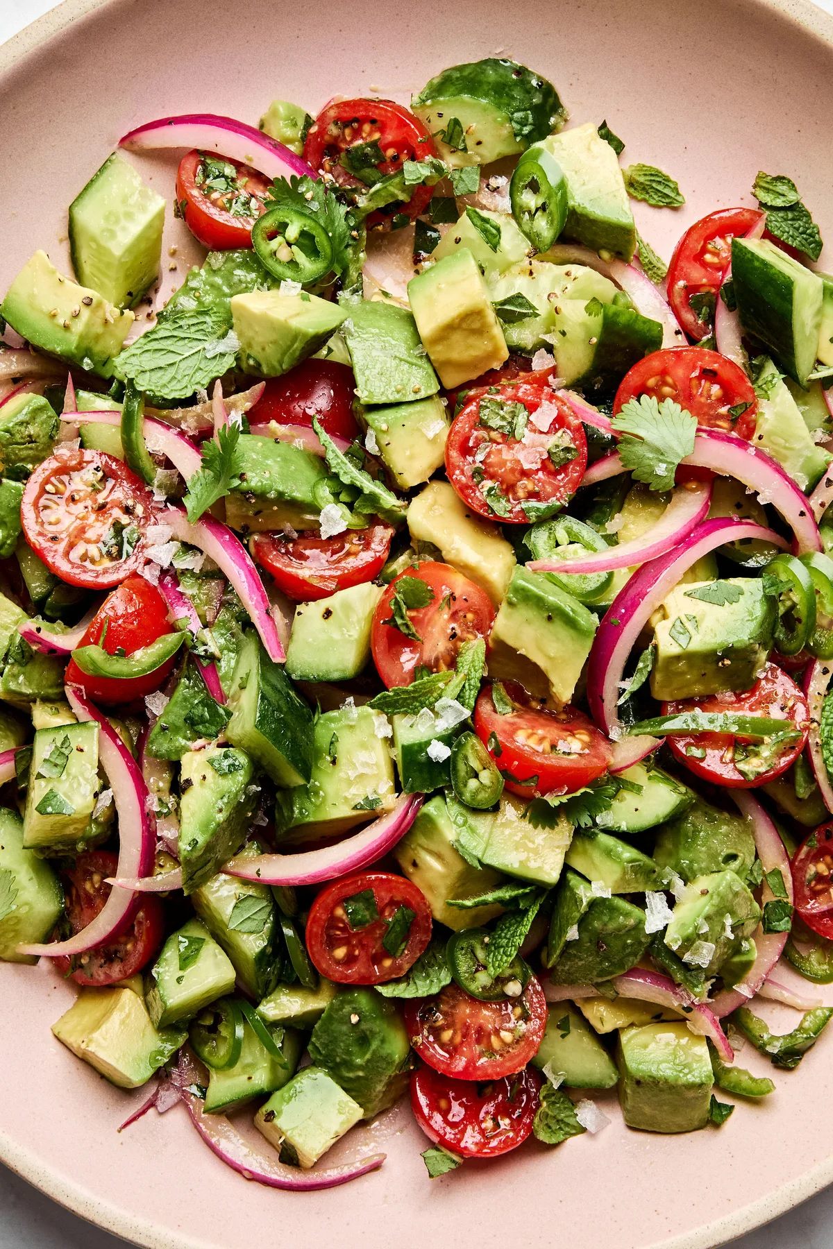avocado salad made with tomatoes, cucumbers, serrano pepper, herbs and homemade vinaigrette topped with flaky salt