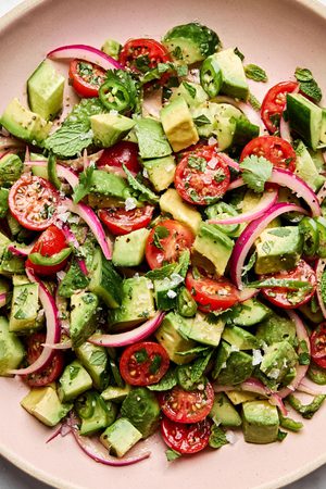 avocado salad made with tomatoes, cucumbers, serrano pepper, herbs and homemade vinaigrette topped with flaky salt