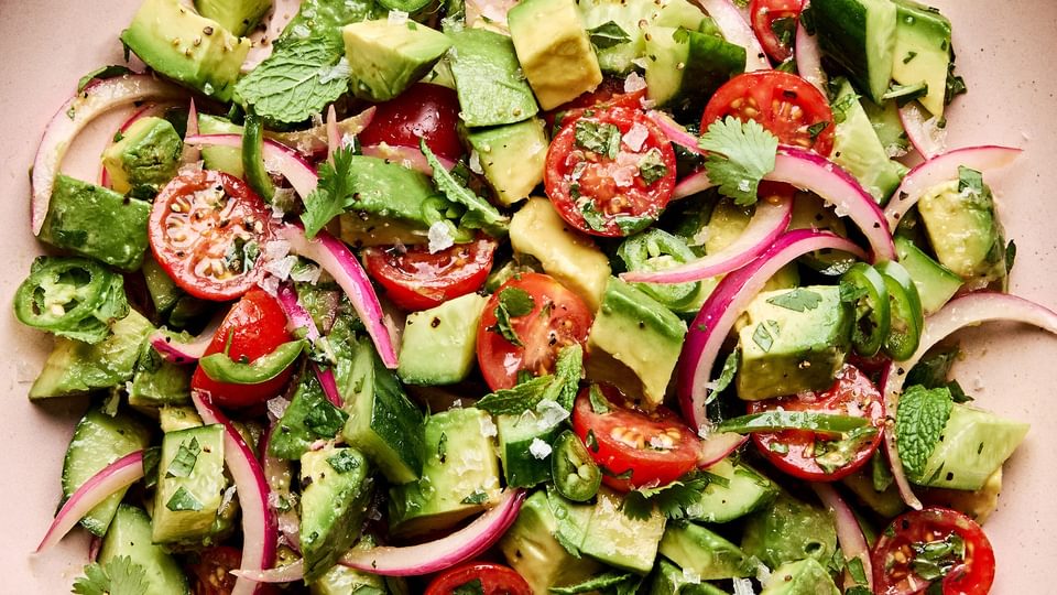 avocado salad made with tomatoes, cucumbers, serrano pepper, herbs and homemade vinaigrette topped with flaky salt