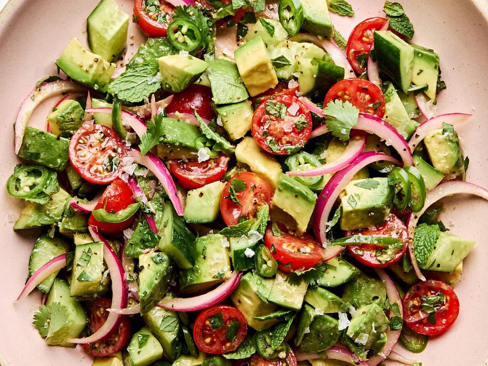 avocado salad made with tomatoes, cucumbers, serrano pepper, herbs and homemade vinaigrette topped with flaky salt