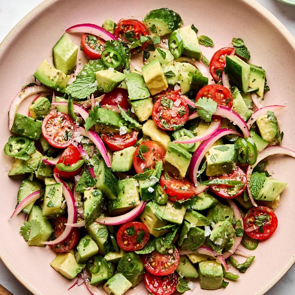 avocado salad made with tomatoes, cucumbers, serrano pepper, herbs and homemade vinaigrette topped with flaky salt