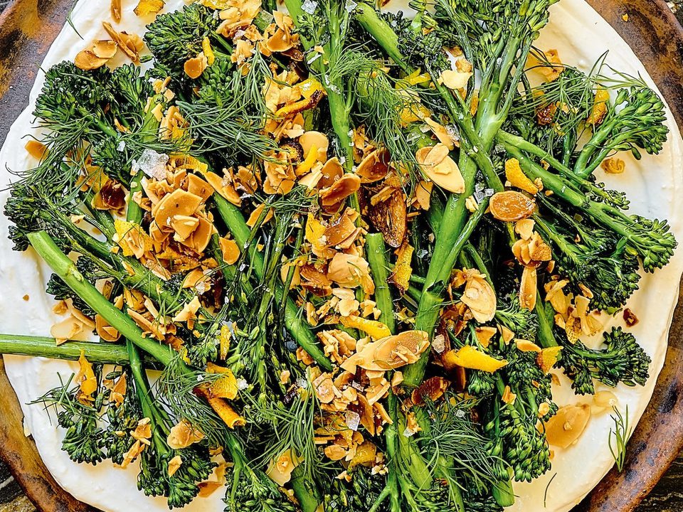 a plate of crispy air fried baby broccoli on top of whipped cottage cheese sprinkled with lemon garlic crisp and fresh dill