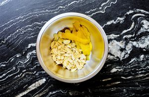 sliced garlic, lemon peel, almonds being tossed with olive oil to make a lemon garlic crisp
