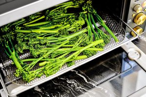 baby broccoli being cooked in an air fryer