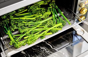 baby broccoli being cooked in an air fryer