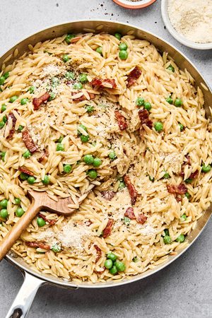 a pan of homemade creamy orzo pasta with bacon, peas and parmesan