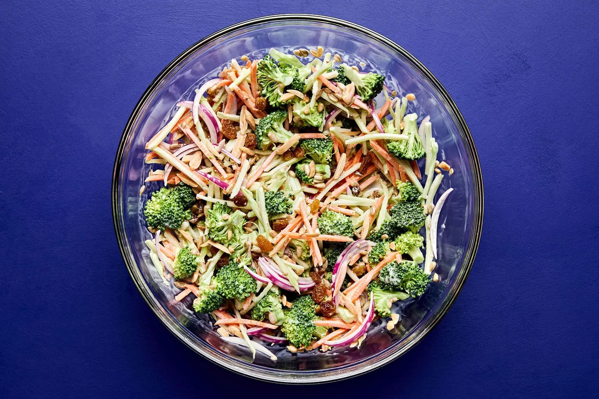 A bowl of fresh broccoli slaw with shredded carrots and cranberries and almonds, tossed in a light dressing.