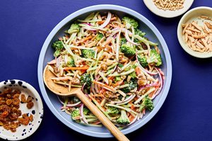 A bowl of fresh broccoli slaw with shredded carrots and cranberries and almonds, tossed in a light dressing.