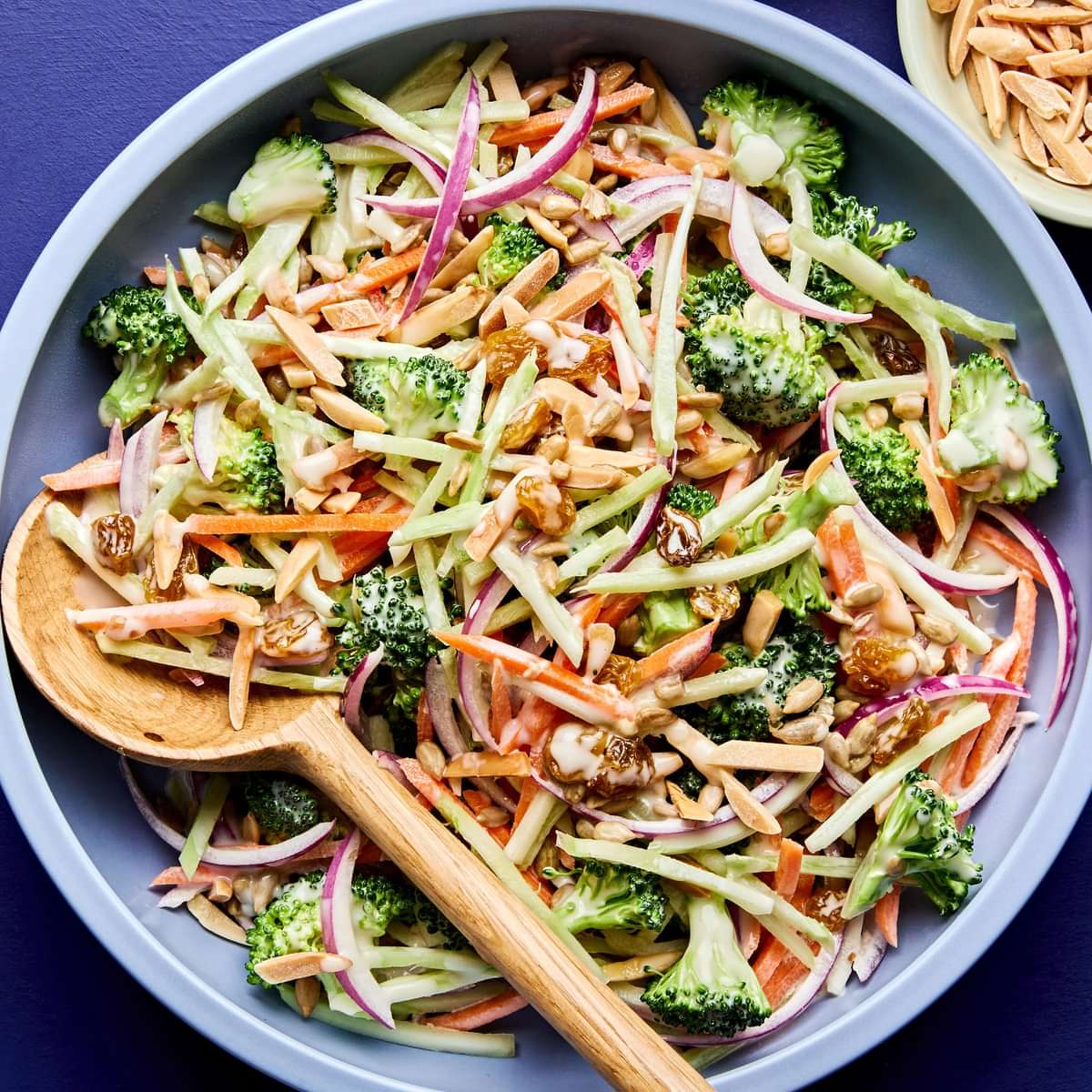 A bowl of fresh broccoli slaw with shredded carrots and cranberries and almonds, tossed in a light dressing.
