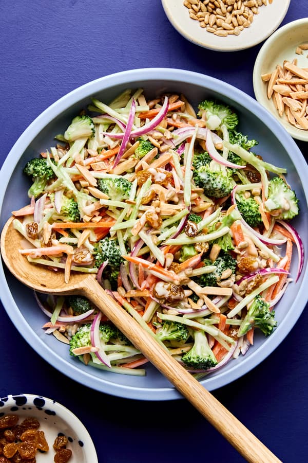A bowl of fresh broccoli slaw with shredded carrots and cranberries and almonds, tossed in a light dressing.