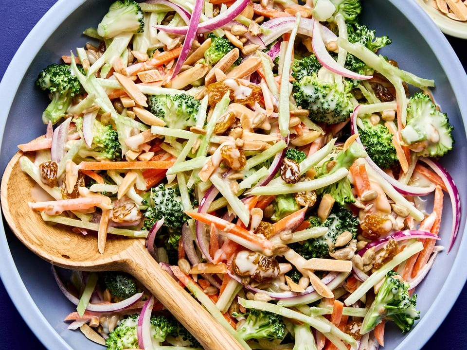 A bowl of fresh broccoli slaw with shredded carrots and cranberries and almonds, tossed in a light dressing.