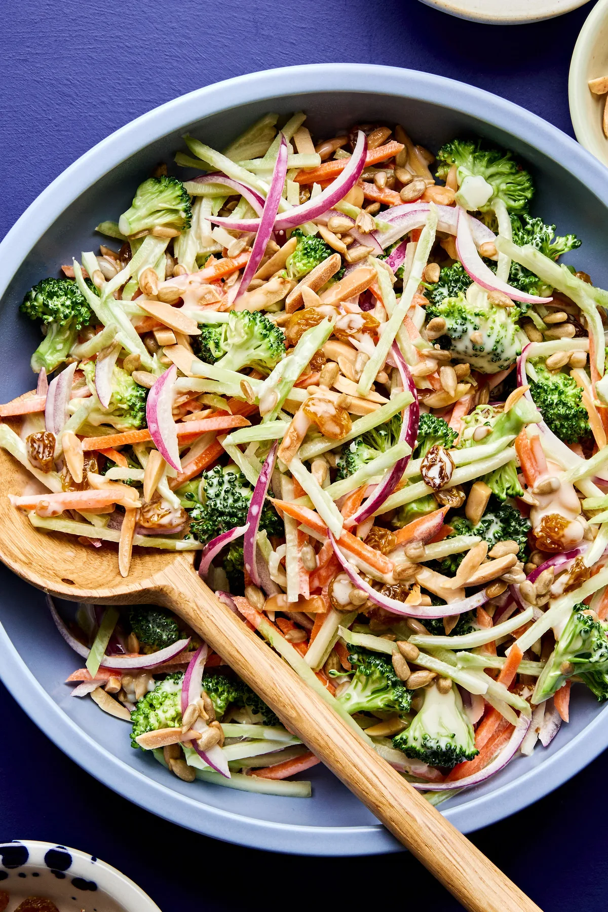 A bowl of fresh broccoli slaw with shredded carrots and cranberries and almonds, tossed in a light dressing.
