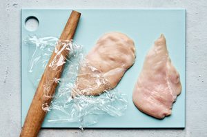 chicken breast being pounded thin with a rolling pin prepping to make chicken fried chicken with creamy gravy