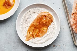 chicken breast pounded thin being dredged in flour to make chicken fried chicken, a classic southern dinner