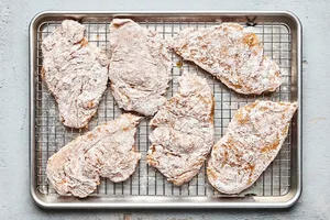 chicken breasts seasoned and dredged with flour ready to be fried into chicken fried chicken