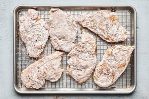 chicken breasts seasoned and dredged with flour ready to be fried into chicken fried chicken