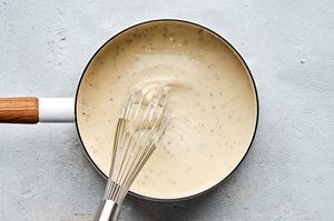 Creamy country gravy being stirred in a skillet, made from scratch with chicken stock, butter, flour, milk and spices