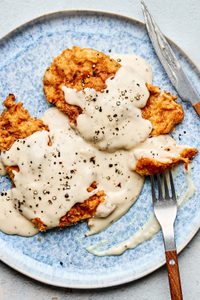 Crispy chicken fried chicken topped with creamy country gravy on a plate, a classic Southern comfort food dinner