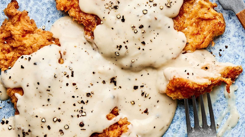 Crispy chicken fried chicken topped with creamy country gravy on a plate, a classic Southern comfort food dinner