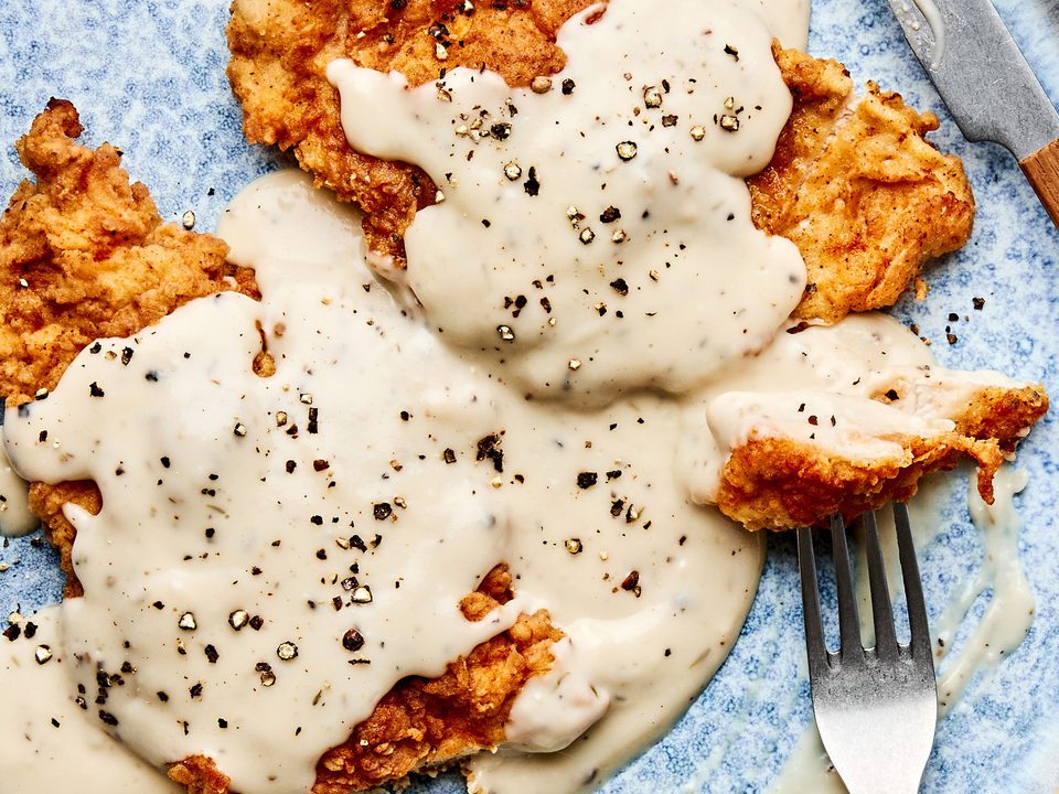 Crispy chicken fried chicken topped with creamy country gravy on a plate, a classic Southern comfort food dinner