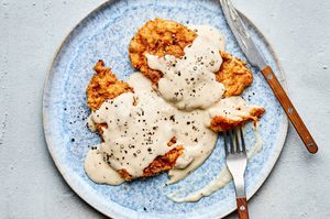 homemade Crispy chicken fried chicken topped with creamy country gravy on a plate, a classic Southern comfort food dinner