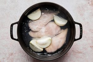 chicken breast, onion and salt boiling in water to make shredded chicken for chipotle chicken flautas