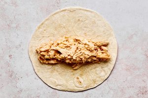 creamy, cheesy chicken filling being rolled in a flour tortillas to make easy weeknight chipotle chicken flautas