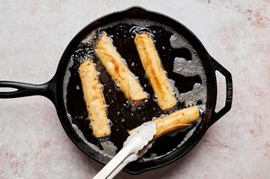 creamy, cheesy chicken chipotle flautas being deep fried in oil in a skillet