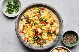 A bowl of creamy homemade corn chowder with potatoes, bell pepper and crispy chopped bacon and topped with green onion