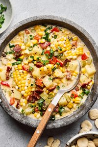 A bowl of creamy homemade corn chowder with potatoes, bell pepper and crispy chopped bacon and topped with green onion