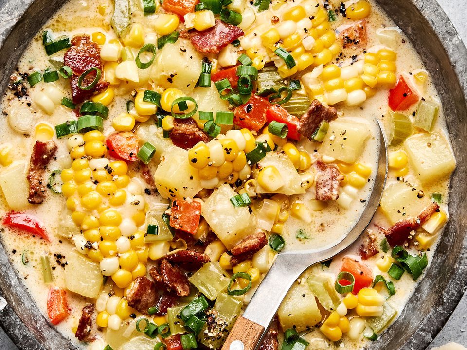 A bowl of creamy homemade corn chowder with potatoes, bell pepper and crispy chopped bacon and topped with green onion