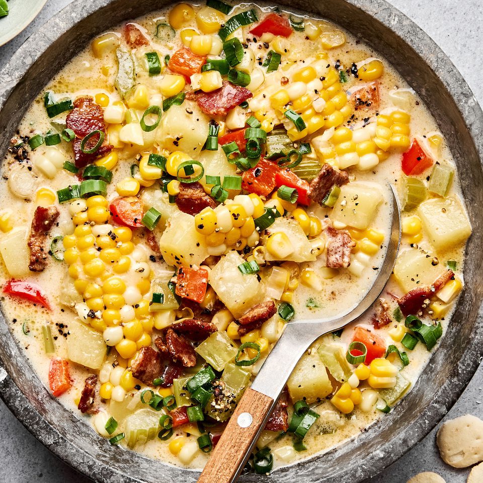 A bowl of creamy homemade corn chowder with potatoes, bell pepper and crispy chopped bacon and topped with green onion