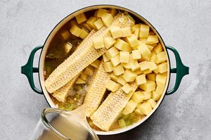potatoes, broth and corn cobs being added to a pot to make homemade corn chowder