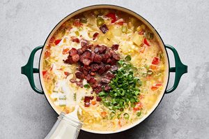 heavy cream, chopped bacon and green onions being stirred into a pot of homemade creamy corn chowder