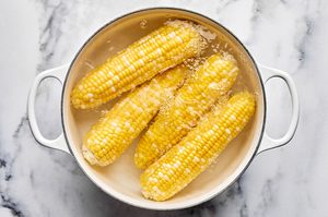 corn on the cob being boiled in a pot to use to make fresh corn salsa