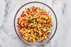 Bowl of fresh corn salsa with diced tomatoes, red onion, jalapeño, cilantro, lime and spices