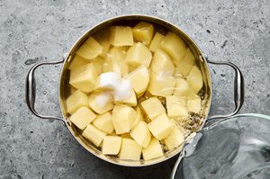 peeled chopped potatoes going into a pot with baking soda and water to make crispy roasted potatoes