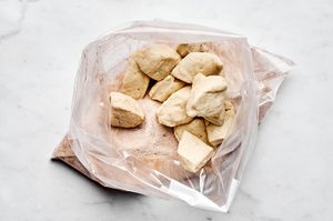 biscuit dough pieces being tossed with sugar and cinnamon until fully coated to make delicious homemade monkey bread