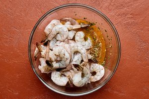raw shrimp being tossed with melted butter and spices to make garlic butter grilled shrimp, a perfect summer meal