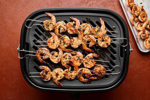 garlic butter shrimp on skewers being cooked on a grill