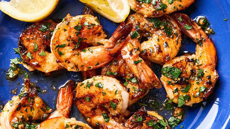 Garlic butter grilled shrimp sprinkled with fresh parsley served on a plate with lemon wedges,a perfect summer seafood meal