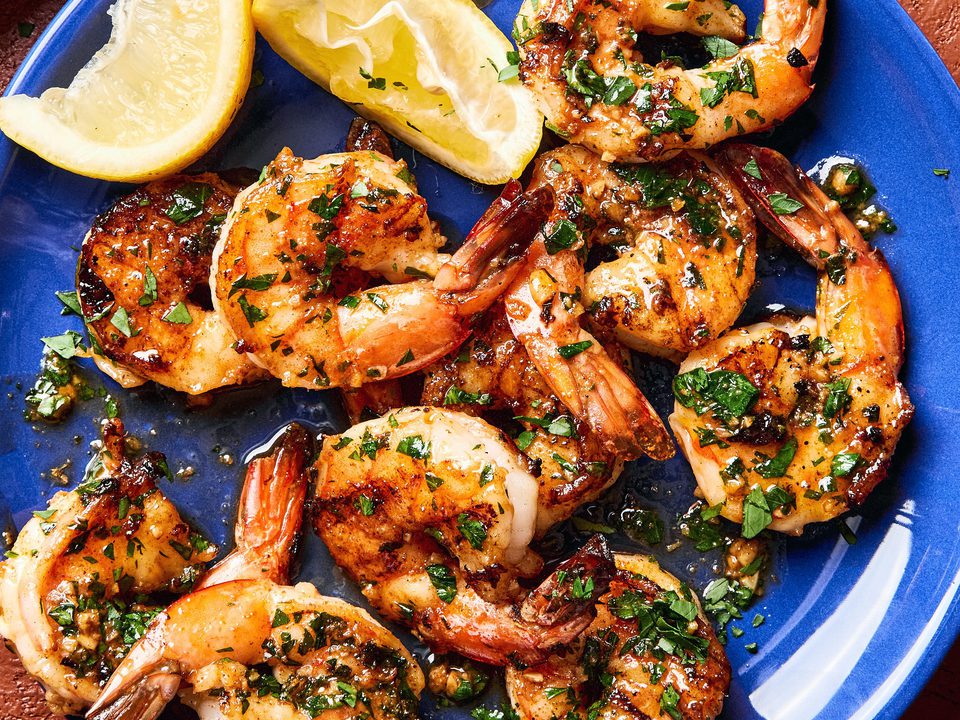 Garlic butter grilled shrimp sprinkled with fresh parsley served on a plate with lemon wedges,a perfect summer seafood meal